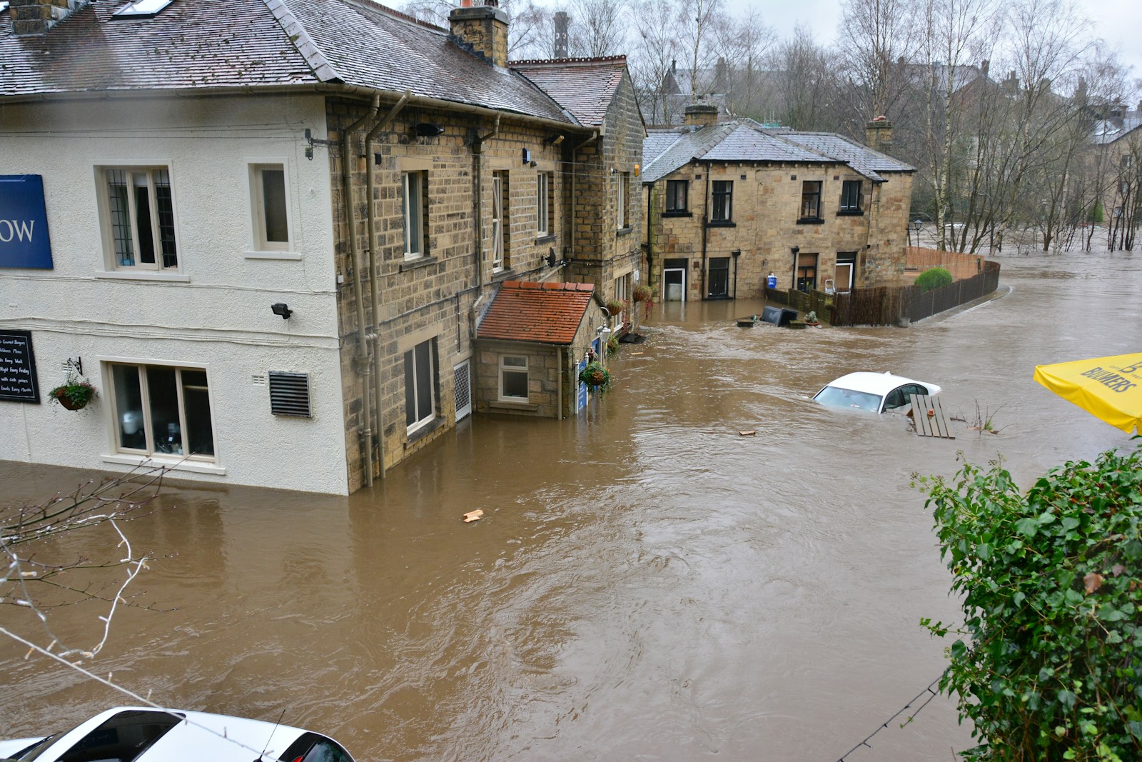 brown and white concrete house beside river during daytime, flood